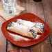 A Fiesta® Scarlet square salad plate with two pastries on it.