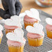 A person holding a cupcake with white Satin Ice Pearl Shimmer fondant shaped like a heart.