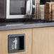 A black Vollrath flush-mount trash receptacle door with a white figure.