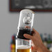 A person holding a glass of beer with a lighted disco lid on it.