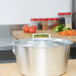A Vollrath Arkadia stainless steel pot with a lid on a wooden surface.