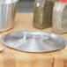 A Vollrath stainless steel lid on a wooden surface.