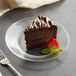 a piece of chocolate cake on a clear plate with a strawberry on top