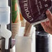 A person pouring UPOURIA Salted Chocolate Caramel Cappuccino mix into a container.