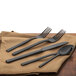 A Walco black stainless steel dessert spoon on a brown napkin.