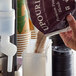 A person pouring UPOURIA Caramel Macchiato Cappuccino mix into a container.