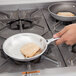 A person using a Vollrath Wear-Ever aluminum fry pan to cook chicken.