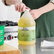 A hand holding a green jug of yellow liquid with a white label for Noble Chemical Arctic Ice Machine Cleaner.