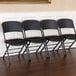 A row of four black Lifetime padded folding chairs.