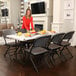 A woman standing at a table with food on it with a Lifetime gray folding padded chair.