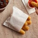 A person holding a Carnival King small French fry bag filled with fried food on a table.