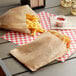 A sandwich and french fries in Carnival King brown paper bags on a table.