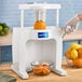 A person using a Sunkist commercial sectionizer to cut an orange.