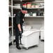 A man in a black uniform and gloves using a white Cambro ingredient storage bin on wheels.