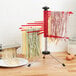 Stainless steel Fox Run pasta drying rack with green pasta drying on the arms.