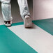 A person wearing white shoes and white pants standing on a white Cactus Contaminate Control dry mat.