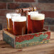 A GET reclaimed wood condiment caddy holding beer glasses on a table in a brewery tasting room.