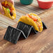 A person holding a taco in an American Metalcraft black faux-slate melamine taco holder.
