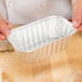 A person holding a silver D&W foil bread loaf pan.