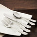 A white plate with a Walco Goddess stainless steel knife and spoon on it.