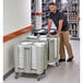 A man pushing a Cambro dish dolly full of plates.