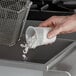 A hand pouring Noble Chemical Fryclone white powder into a container.