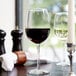 A Libbey Vina wine glass filled with red wine on a table in an Italian restaurant.