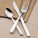 A Libbey stainless steel iced tea spoon and a fork on a napkin.