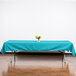 A table with a teal Intedge tablecloth and a bouquet of flowers on it.