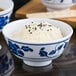 A close up of a Thunder Group Lotus melamine rice bowl filled with rice and black sesame seeds.