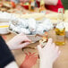 A woman using a 40" x 100' paper table cover with a crab pattern on a table while eating crab.