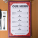 Burgundy menu paper with an angled marble border on a table with a fork and knife.