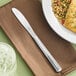 A Libbey stainless steel dinner knife on a plate of food.