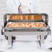 A person in a white glove using a Vollrath Avenger chafing dish to serve food.