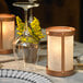 A table set with a wine glass and a Sterno Copper Frost votive candle holder with a lit candle.