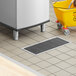 A Regency stainless steel floor trough with a yellow bucket under it.