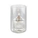 A Sterno clear glass votive candle holder with a lit candle inside.