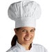 A woman wearing a white Mercer Culinary chef hat smiling.