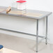 An Advance Tabco stainless steel work table with a rolling pin and flour container on it.