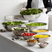 A woman using a Vollrath stainless steel mixing bowl to serve salad at a salad bar.