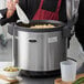 A man using an Avantco non-stick pot in a professional kitchen to cook rice and peas.