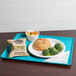 A Cambro dietary tray with a sandwich, broccoli, and potato chips.