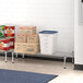 A Regency metal dunnage shelf in a school kitchen with food containers and cans on it.