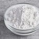 A clear glass bowl filled with white tapioca flour on a gray surface.