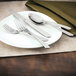 A white plate with a Walco Classic Scroll salad fork and knife on it.