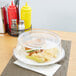 A Carlisle clear polycarbonate plate cover over a plate with a sandwich and chips.