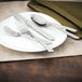 A white plate with a Walco bouillon spoon and silverware on it.