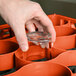 A person using an orange Carlisle glass rack extender to wash glasses.