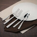 A white plate with a Walco stainless steel knife and spoon on it.