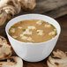 A white Carlisle melamine bouillon cup filled with soup and mushrooms.